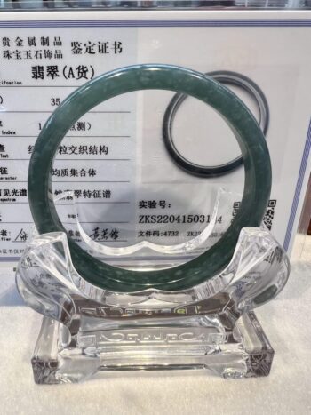 A green jade bangle is sitting on top of a glass stand.