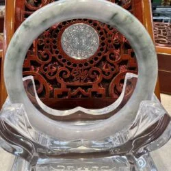 A large white jade ring sitting on top of a glass stand.