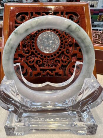 A large white jade ring sitting on top of a glass stand.