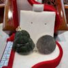 A green stone buddha sitting on top of a red pillow.