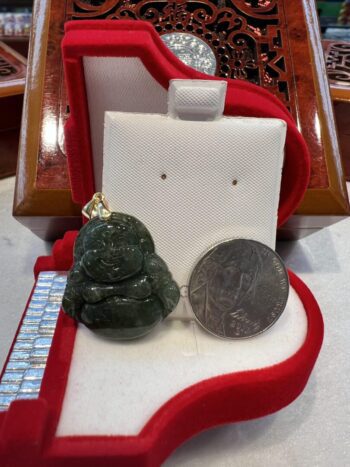 A green stone buddha sitting on top of a red pillow.