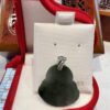 A green pear shaped earring sitting on top of a white display.