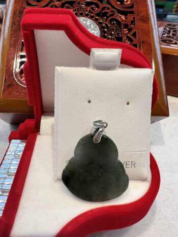 A green pear shaped earring sitting on top of a white display.