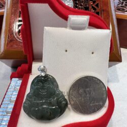 A small buddha statue sitting next to a coin.