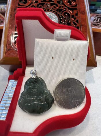 A small buddha statue sitting next to a coin.