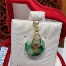 A green and white pendant sitting on top of a red pillow.