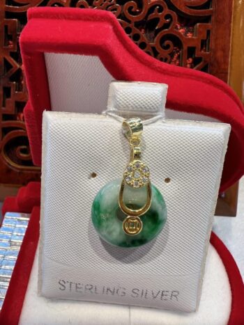 A green and white pendant sitting on top of a red pillow.