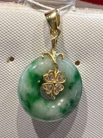 A green and white pendant with four leaf clover.