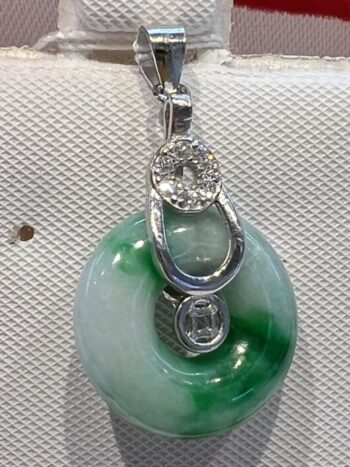 A green and white pendant on a silver chain.