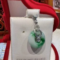 A silver bag with a green glass charm on it.