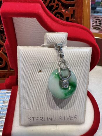 A silver bag with a green glass charm on it.