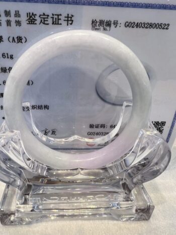 A white bracelet sitting on top of a clear glass.