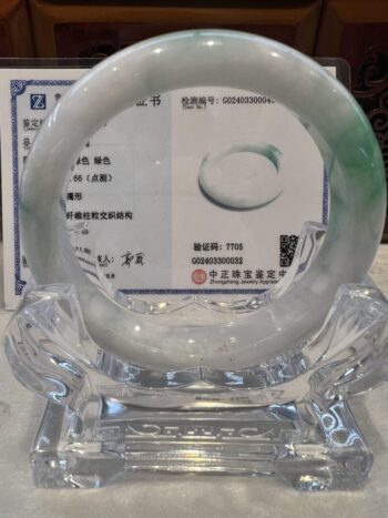 A clear glass display case with a green and white ring.