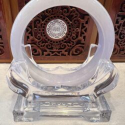 A clear glass sculpture with a white ring on top.