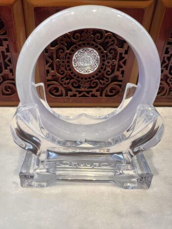 A clear glass sculpture with a circular design.