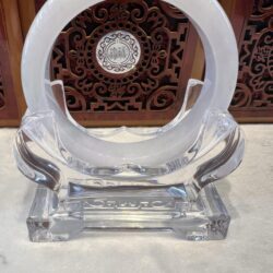 A clear glass sculpture with a white circle on top.