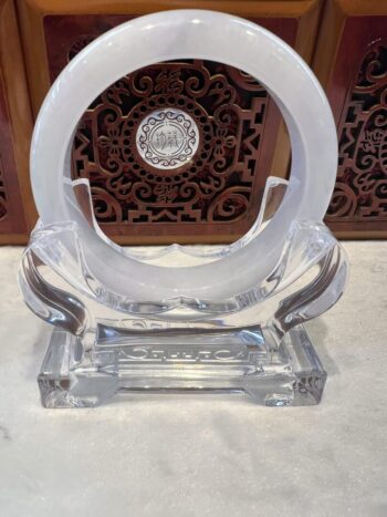 A clear glass sculpture with a white circle on top.