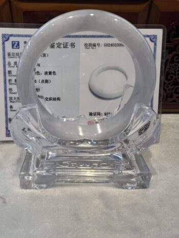 A clear glass sculpture with a white circle on top.