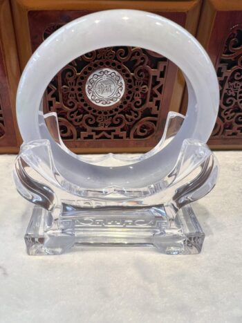 A clear glass sculpture with a white ring on top.