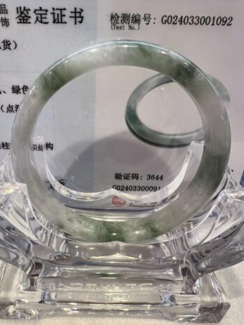 A green and white bracelet sitting on top of a glass table.