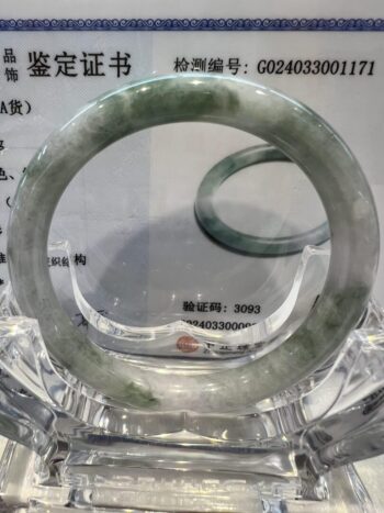 A green and white bracelet sitting on top of a glass table.