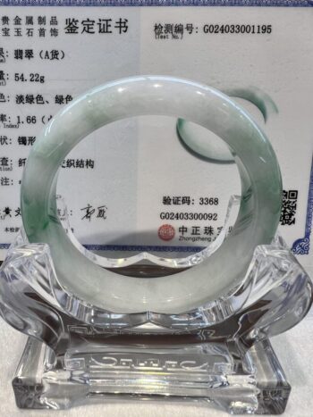 A green and white bracelet sitting on top of a glass table.