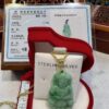 A green jade buddha pendant sitting in a red box.