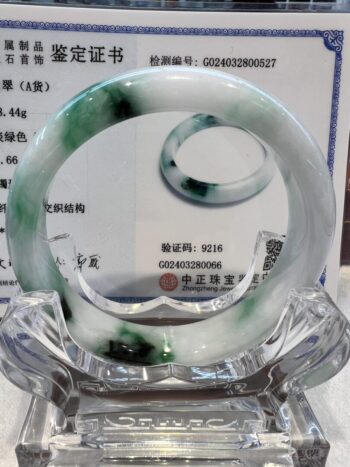 A green and white bracelet sitting on top of a glass display.