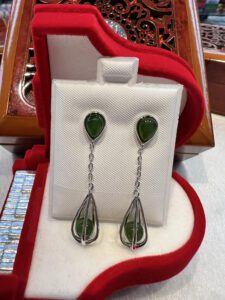 A pair of earrings with green stones in silver.