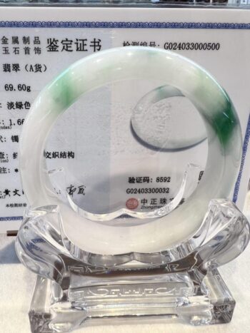 A green and white bangle sitting on top of a clear glass.