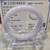 A white jade bangle sitting on top of a clear glass display.