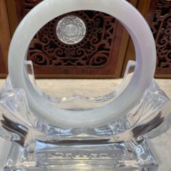 A clear glass sculpture with a white ring on top.