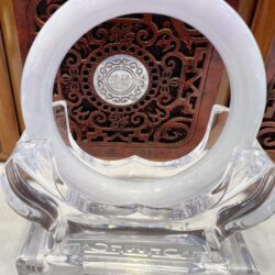 A clear glass sculpture with a white ring on top.