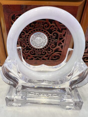 A clear glass sculpture with a white ring on top.