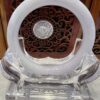 A clear glass sculpture with a white ring on top.