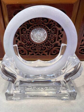 A white ring sitting on top of a clear glass sculpture.