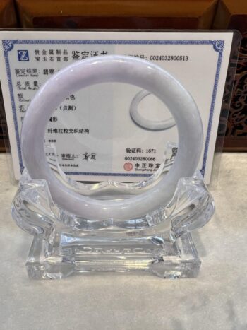 A white jade bangle sitting on top of a glass table.