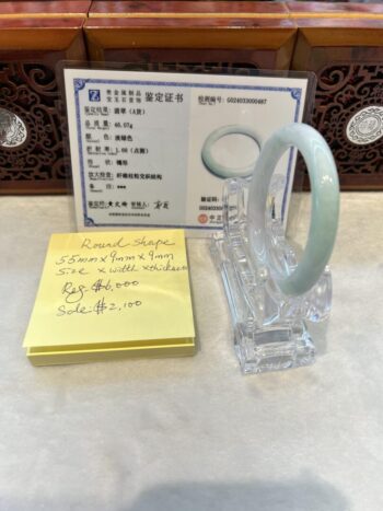 A glass pen holder with some papers and a green bracelet