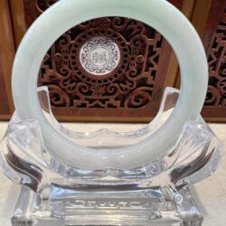 A white jade ring sitting on top of a clear glass holder.