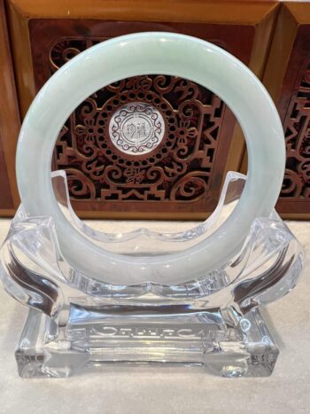 A white jade ring sitting on top of a clear glass holder.