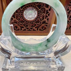 A green and white bracelet sitting on top of a glass table.