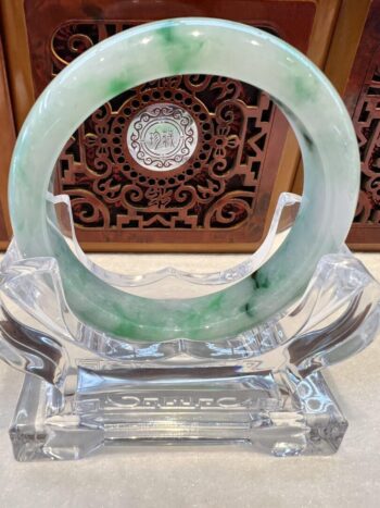 A green and white bracelet sitting on top of a glass table.