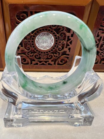 A green and white bracelet sitting on top of a glass table.