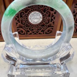 A green and white bracelet sitting on top of a glass holder.