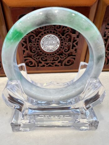 A green and white bracelet sitting on top of a glass holder.