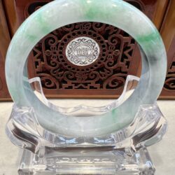 A green and white jade bangle sitting on top of a stand.