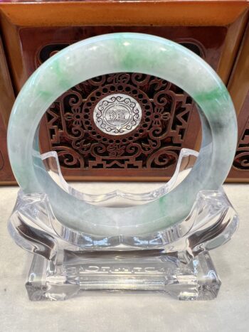 A green and white jade bangle sitting on top of a stand.