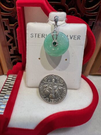 A silver necklace sitting next to a coin.