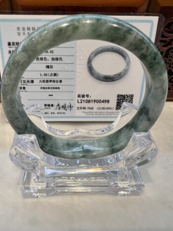 A green jade bangle sitting on top of a clear glass table.