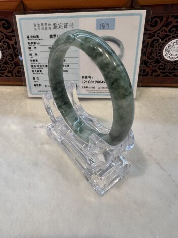 A green bracelet is sitting on top of a clear stand.